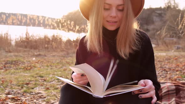 Millennial Woman Slow Motion Caucasian Blonde Woman with Beige Hat in Black Sweater Reads Book in