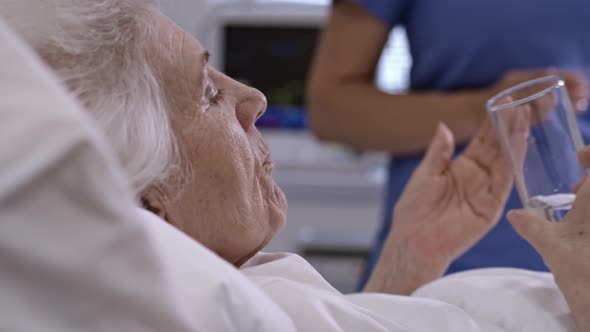 Nurse Giving Medications to Senior Woman in Hospital