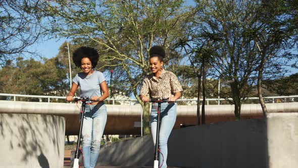 Two mixed race women riding electric scooter