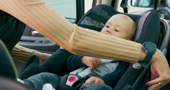 Closeup Baby Boy Who Sits in the Baby Car Seat Inside of Car Door Opens and His Mother's Hands