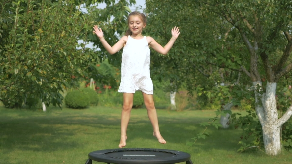 Little Girl Jumping on Trampoline in Garden