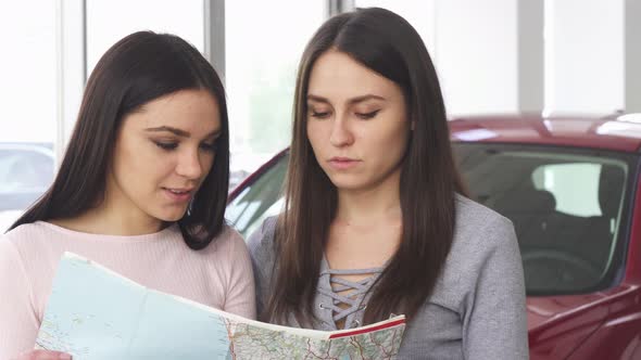 Two Beautiful Female Friends Looking for Destination on a Map
