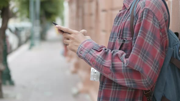 Tourists Asian man using a smartphone checking social media while standing beside the street.