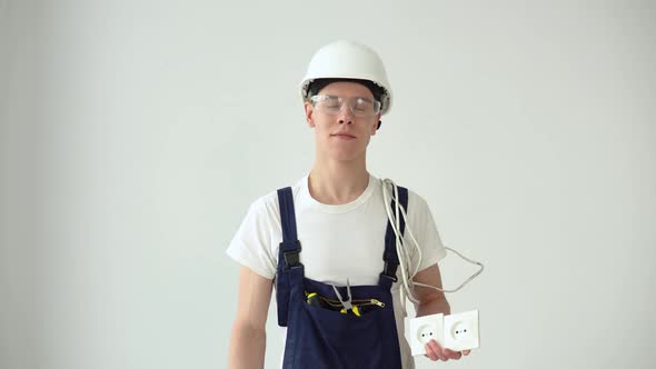 The Electrician Holds the Sockets in His Hand and Looks Straight Ahead