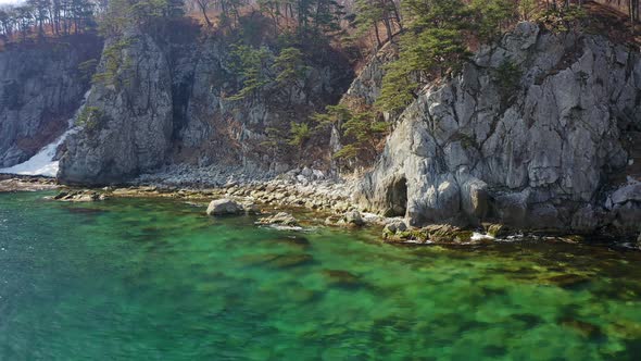 Aerial View of the Rocky Seashore of a Beautiful Bay with Transparent Water