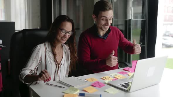 Cheerful Business Man and Woman with Laptop Discussing Project