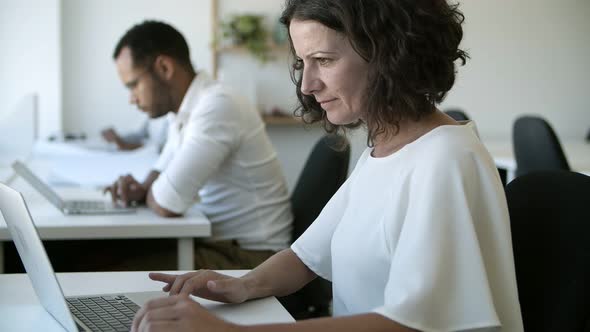 Side View of Focused Caucasian Woman Working with Laptop