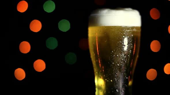 A Glass of Cold Beer on a Black Background with Colored Lights