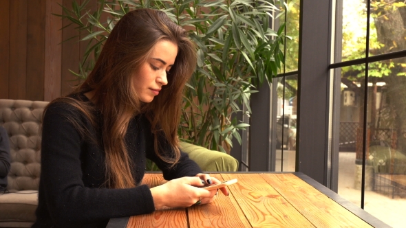 Young Woman at Cafe Using Mobile Phone