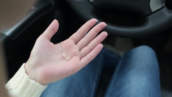 girl puts antiseptic gel on her hands in a car and disinfects her skin