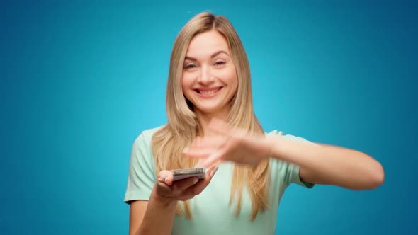 Young Woman Showing Gesture of Wasting Money Against Blue Background Materialist Shopping Concept