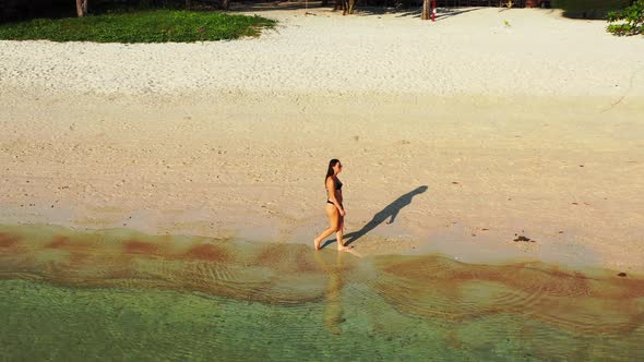 Beautiful smiling ladies on photoshoot having fun at the beach on summer white sand and blue 4K back