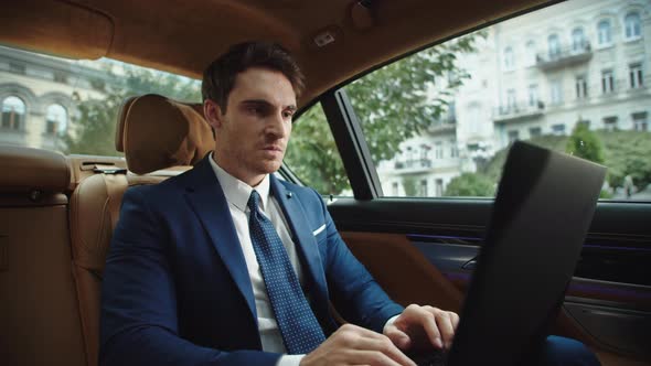 Angry Male Ceo Typing Laptop Computer in Luxury Car