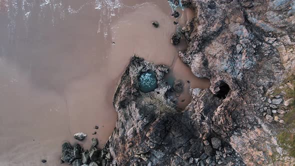 AERIAL: Slow descend over swirling large rockpool, Blue Pool Bay, 4k Drone
