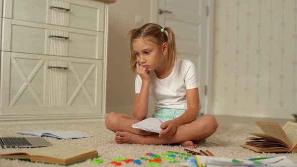 Bored Cheerful Little Schoolgirl Girl Writing By Looking to Laptop Screen During Homeschooling