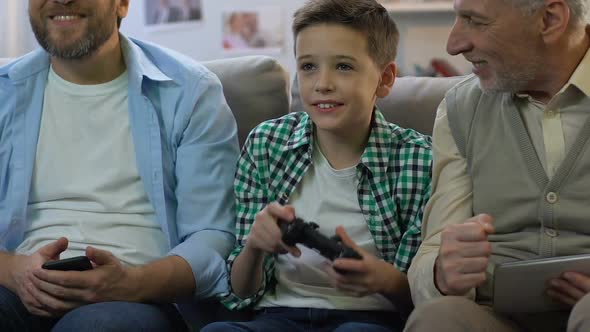 Boy Playing Video Game, Father and Grandpa Holding Gadgets Supporting Child