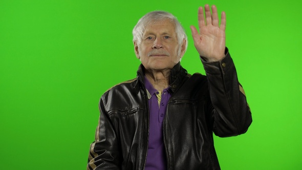 Elderly Caucasian Grandfather Rocker and Biker Man Waves His Hands, Greets