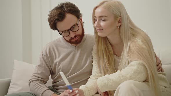 Young Couple Worried About the Results of Pregnancy Test Looking at Each Other with a Concerned Look