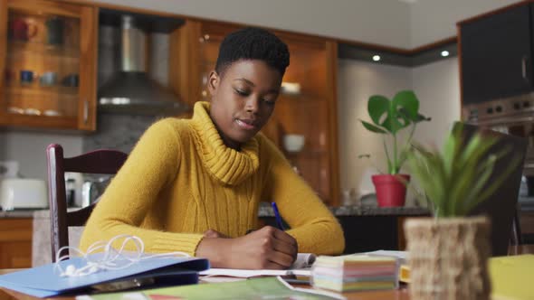 African american woman taking notes while working from home