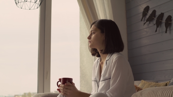 Attractive Girl Looks Out the Window at Cosy Flat