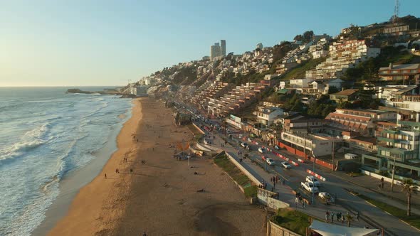 Aerial view flying alongside Avenida Borgoño coastline traffic Reñaca cityscape sunny beach waterfro