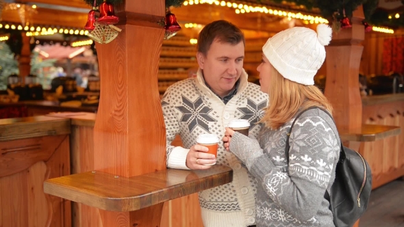 Happy Couple in Warm Clothes Drinking Coffee and Talking on a Christmas Market