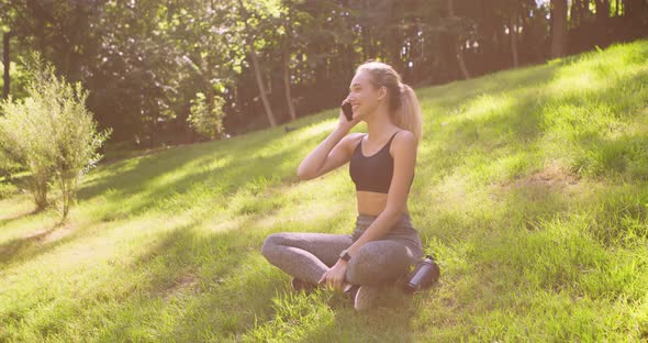 Cheerful Blonde Girl Talking on Cellphone, Resting on Grass