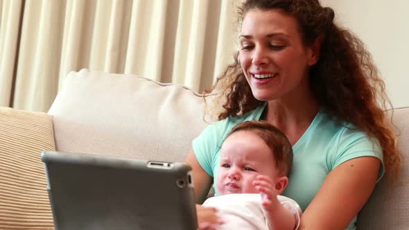 Mother using tablet pc for video chat with baby son on her lap