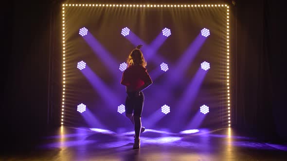 Sportive Girl Actively Dances Jazz Funk in the Center of Blue Spotlight. Silhouette of a Dancer