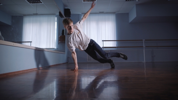 Dancer in White Shirt and Jeans Showing Modern Breakdancing in Classroom with Mirrors and Ballet