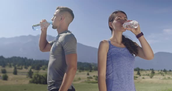 Sportive Young Couple Refreshes Themselves Drinking Fresh Water After the Run