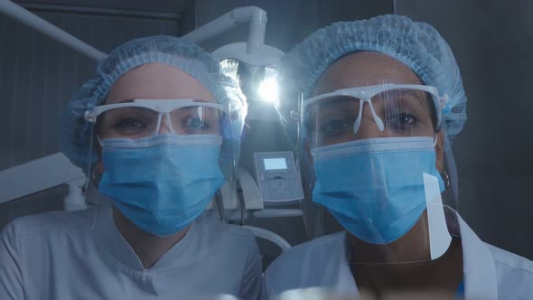 View From Open Mouth of Two Dentists in Safety Mask and Goggles Examining Patient Teeth