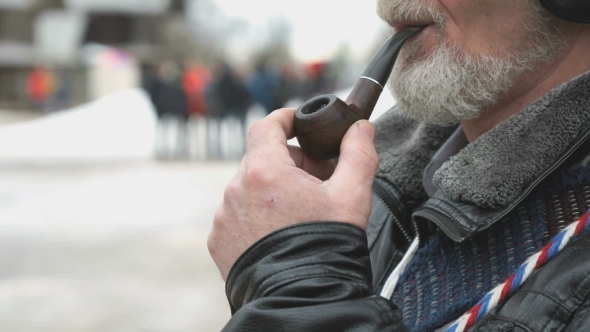 Adult Man with a Beard Smokes Using a Smoking Pipe
