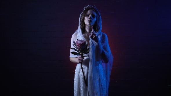 Phantom of Young Lonely Dead Bride Standing with Sad Face and Flower in Her Hand. Scary Girl