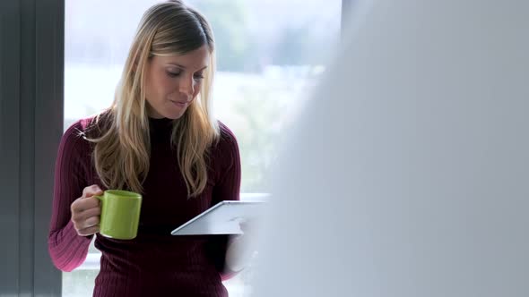 Businesswoman using tablet and drinking in office