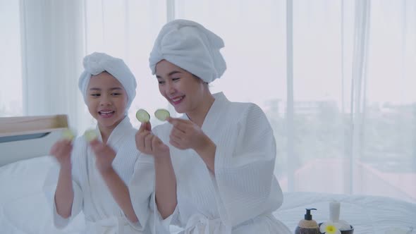 Spa concept. Mom and daughter are having fun with cucumber facials. 4k Resolution.