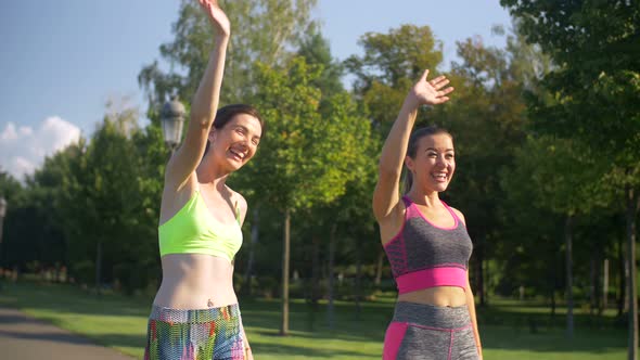 Joyful Sporty Fit Women Greeting Friends in Park