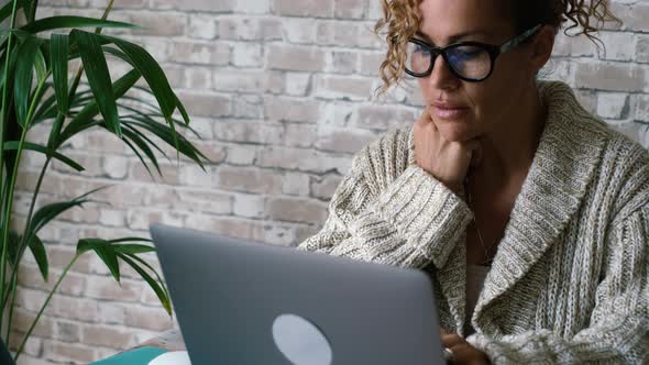 Serene woman work with notebook at home smiling at the display. Serene female use laptop