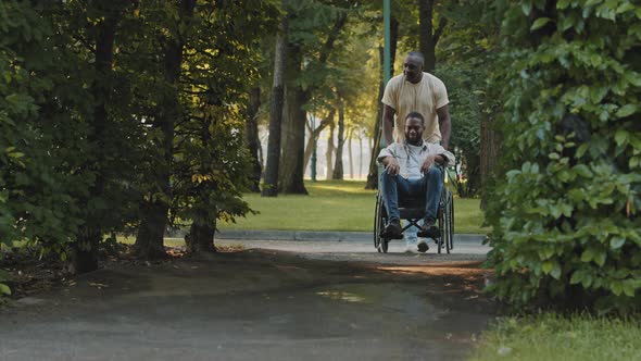 Two Carefree African American Men Walk in Hospital Summer Park Past Sprinklers