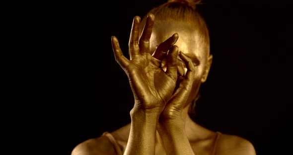 Close-up of Female Hands with Golden Glowing Skin. They Turn, Palms Open and Close. in the