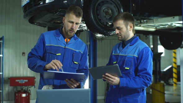 Two Mechanic with a Tablet Recording the Diagnostic Information of the Car