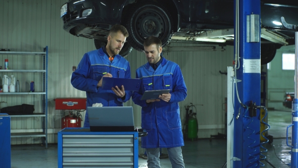 Two Mechanic with a Tablet Recording the Diagnostic Information of the Car