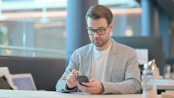 Man Browsing Internet on Smartphone in Office