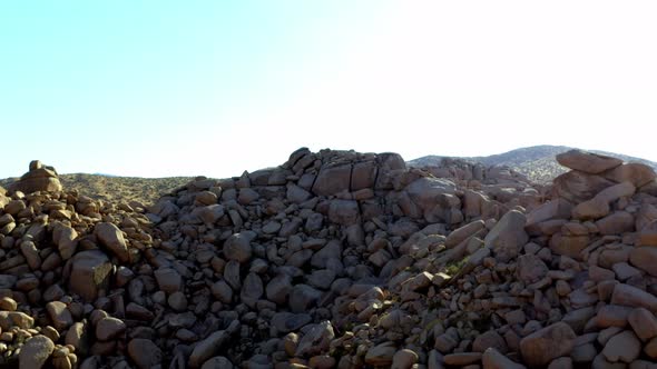 Drone shot flying towards some large rocks in the desert of Pioneertown, California.