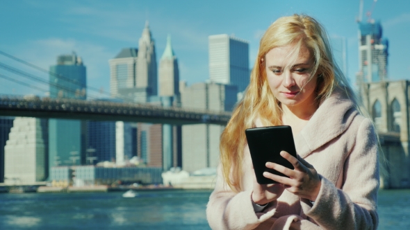 Technology in the Big City. Young Woman Enjoying a Plate Against the Background of Brooklyn Bridge