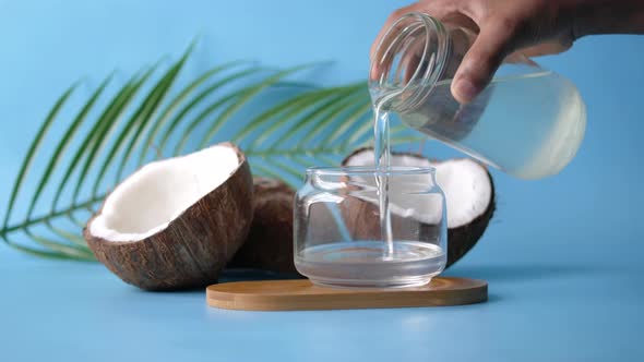 Pouring Coconut Oil in a Container on Blue Background