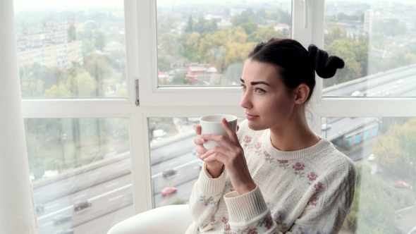 Charming Young Woman Sitting Near Window and Drink Coffee