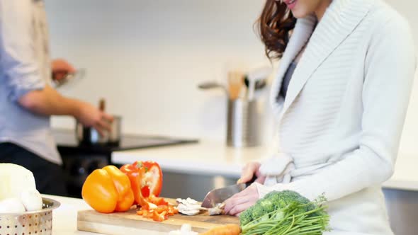 Woman interacting while chopping vegetables in kitchen