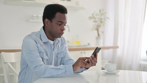 African Man Celebrating Success on Smart Phone