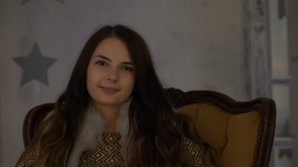 Footage Girl Sitting on a Chair and Looks Into the Camera